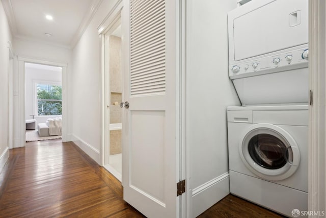 washroom with dark wood-style flooring, crown molding, stacked washer / dryer, laundry area, and baseboards