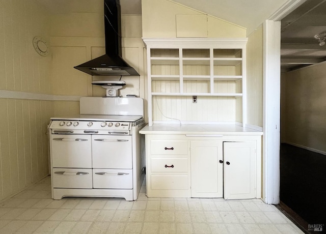 kitchen with wall chimney exhaust hood, white cabinets, white stove, and wood walls