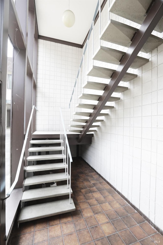 stairway featuring tile walls and ornamental molding