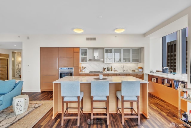 301 Mission St Unit 40D, San Francisco, CA 94105 - kitchen with stainless steel oven, a breakfast bar, glass insert cabinets, dark wood-type flooring, and a sink