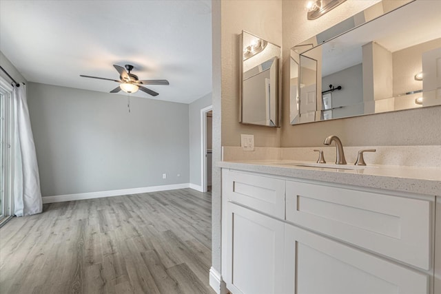 bathroom featuring ceiling fan, vanity, baseboards, and wood finished floors