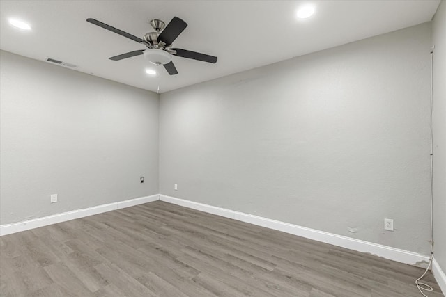 unfurnished room with a ceiling fan, visible vents, baseboards, and wood finished floors