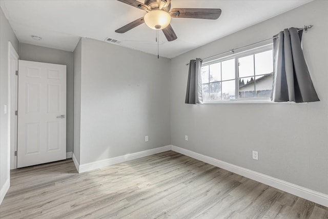 spare room with a ceiling fan, visible vents, baseboards, and wood finished floors