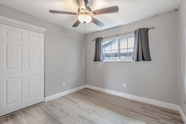 unfurnished bedroom featuring a closet, wood finished floors, a ceiling fan, and baseboards