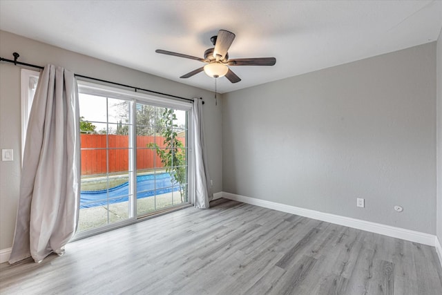 spare room featuring a ceiling fan, baseboards, and wood finished floors