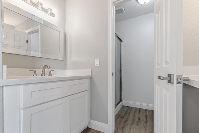 full bath featuring visible vents, a stall shower, vanity, wood finished floors, and baseboards