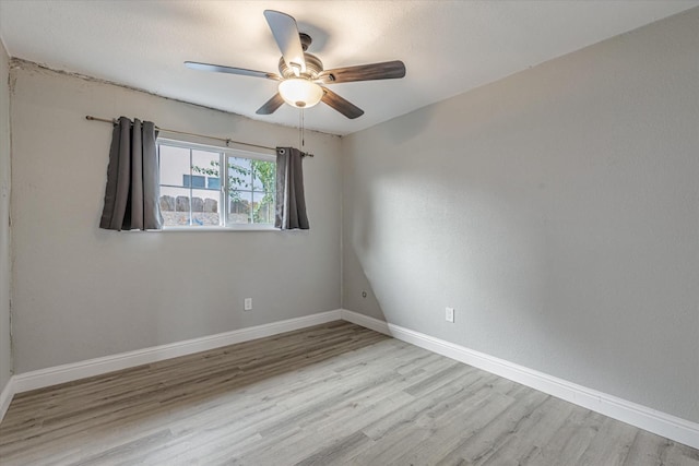 spare room with a ceiling fan, baseboards, and wood finished floors