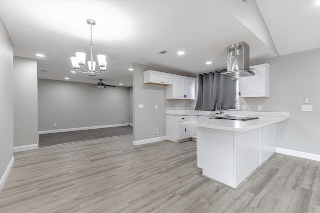 kitchen with light countertops, visible vents, light wood-style flooring, white cabinetry, and a peninsula