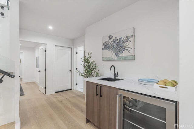 bar featuring beverage cooler, light hardwood / wood-style floors, and sink