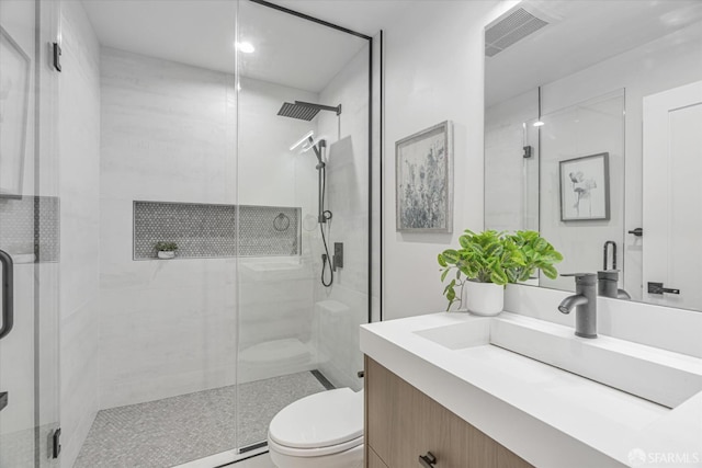 bathroom featuring vanity, a shower with shower door, and toilet