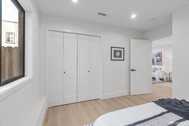 bedroom with light hardwood / wood-style floors and a closet