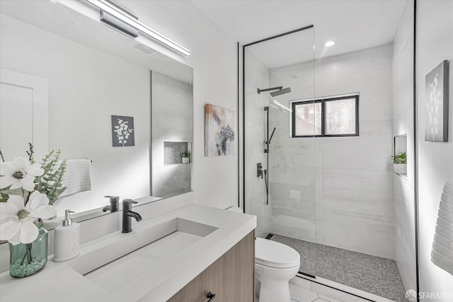 bathroom featuring vanity, toilet, and a tile shower