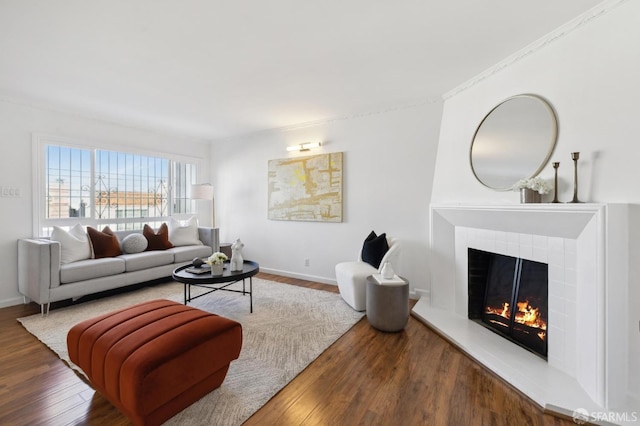 living room with wood-type flooring and a tiled fireplace