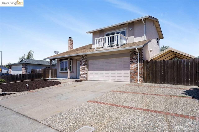 traditional home with a balcony, an attached garage, fence, and concrete driveway