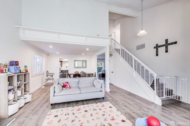 living area with stairway, wood finished floors, a towering ceiling, and baseboards