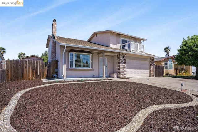 traditional home with stucco siding, an attached garage, fence, a balcony, and driveway