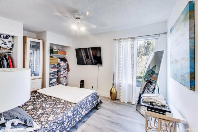 bedroom with a textured ceiling, ceiling fan, a closet, and wood finished floors