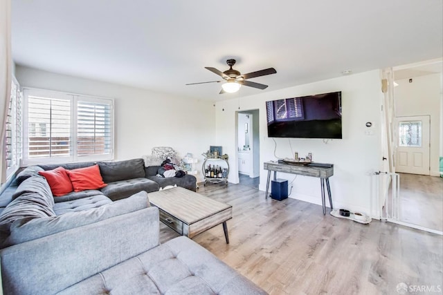 living room featuring a ceiling fan, baseboards, and wood finished floors