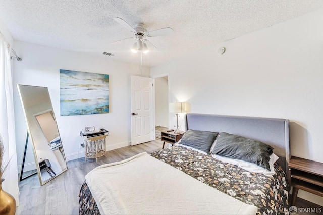 bedroom featuring light wood-style floors, visible vents, and a textured ceiling