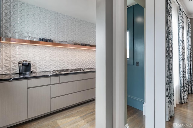 kitchen featuring backsplash, light hardwood / wood-style floors, and stainless steel gas cooktop