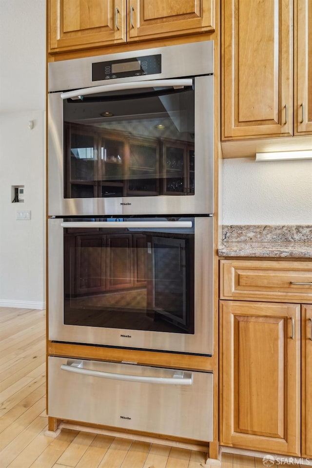 12553 Parker Ranch Ct, Saratoga, CA 95070 - kitchen view of double oven, a warming drawer, light stone countertops, light wood-style flooring, and baseboards