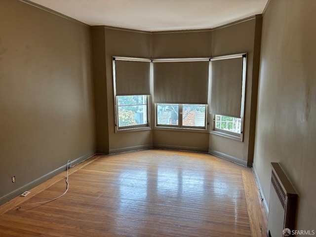 spare room featuring plenty of natural light, radiator heating unit, baseboards, and wood finished floors