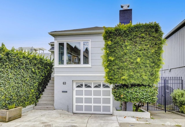 view of side of home with an attached garage, fence, stairway, stucco siding, and a chimney