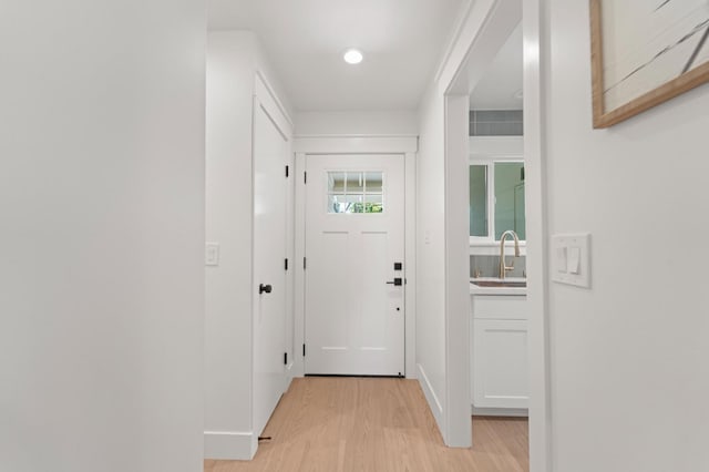 entryway with light wood finished floors, a sink, and baseboards