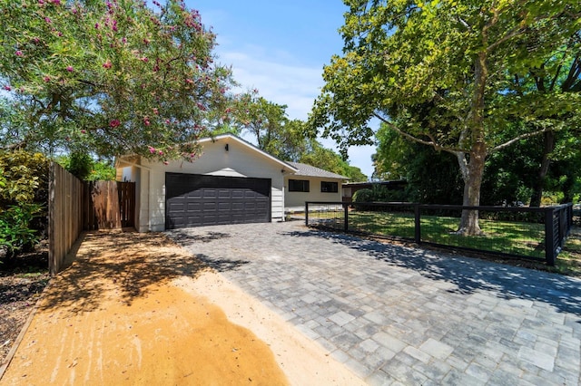 ranch-style house with a garage, fence, and decorative driveway