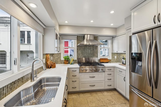 kitchen with white cabinetry, sink, decorative backsplash, stainless steel appliances, and wall chimney exhaust hood