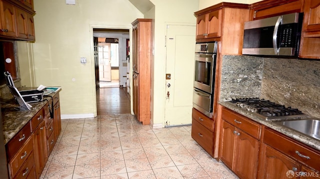 kitchen featuring light hardwood / wood-style flooring, decorative backsplash, stainless steel appliances, and dark stone counters