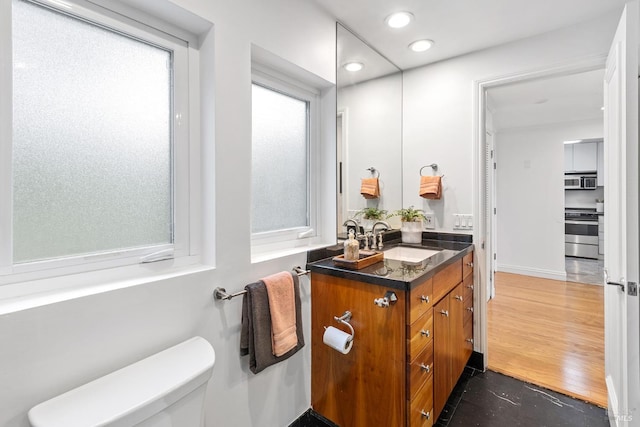 half bath featuring recessed lighting, toilet, and vanity
