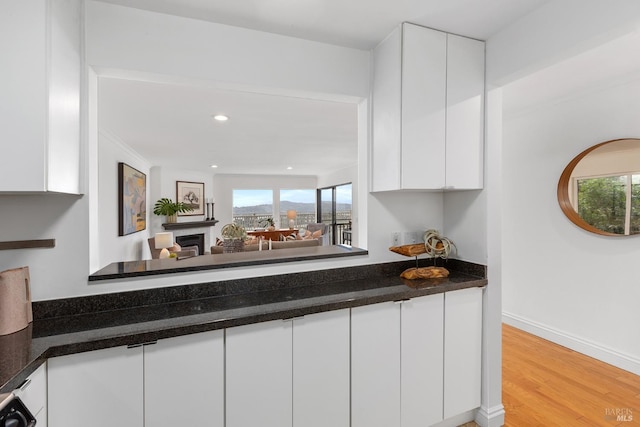 interior space featuring white cabinetry, dark countertops, baseboards, light wood-type flooring, and recessed lighting