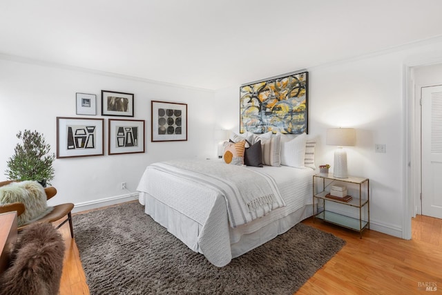 bedroom with crown molding, wood finished floors, and baseboards