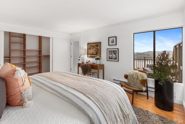 bedroom featuring light wood-type flooring, crown molding, and a closet