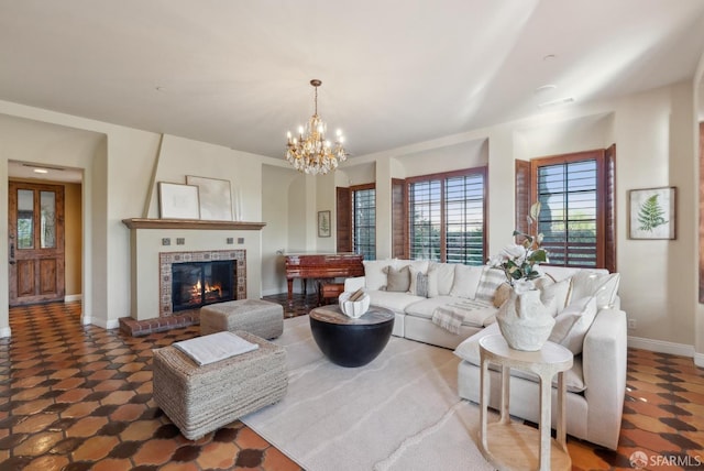 living room with a notable chandelier, a brick fireplace, and baseboards