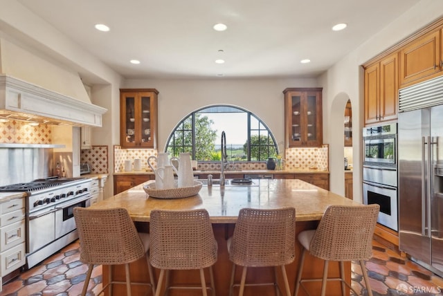 kitchen featuring backsplash, light stone countertops, custom exhaust hood, and high end appliances