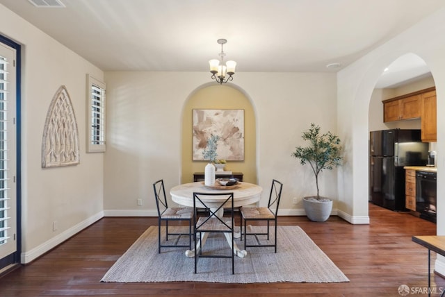 dining area featuring dark wood-type flooring, a notable chandelier, and baseboards