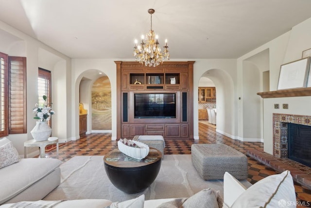 living area featuring arched walkways, a notable chandelier, a fireplace, and baseboards