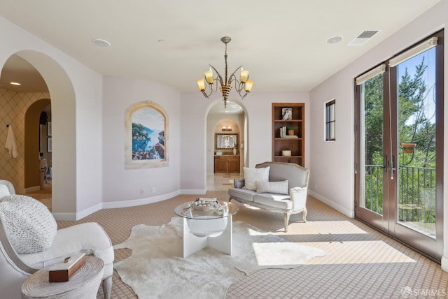 living area featuring visible vents, baseboards, built in features, arched walkways, and a notable chandelier