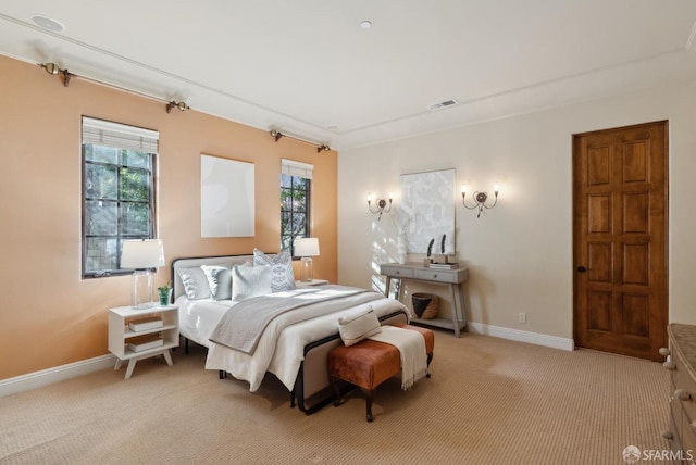 bedroom with baseboards, visible vents, and light carpet