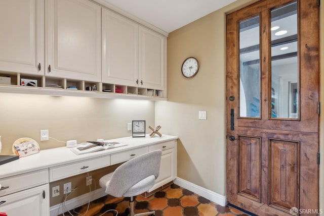 home office featuring built in study area and baseboards