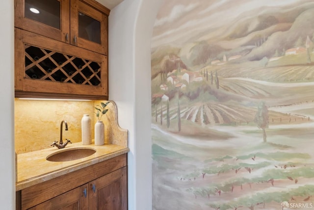 interior space with decorative backsplash, wet bar, and a sink