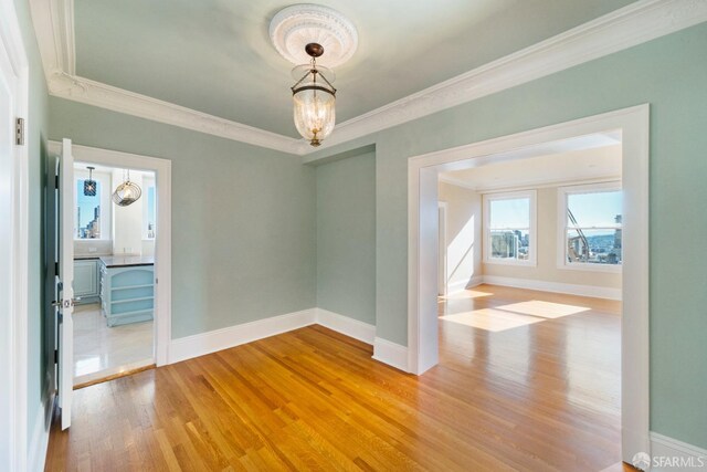 empty room with wood-type flooring and crown molding