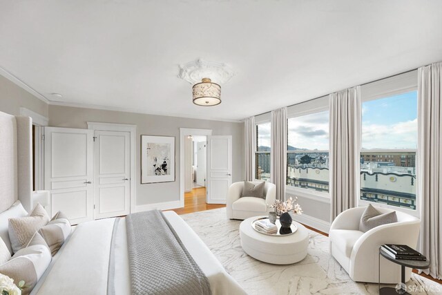 interior space with light wood-type flooring, a water view, and ornamental molding