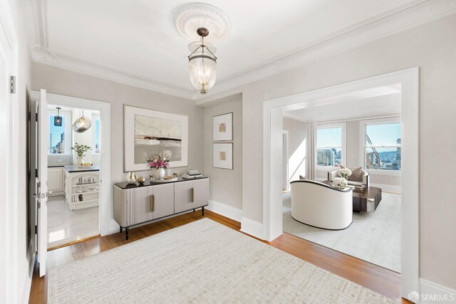 interior space with an inviting chandelier, wood-type flooring, and crown molding