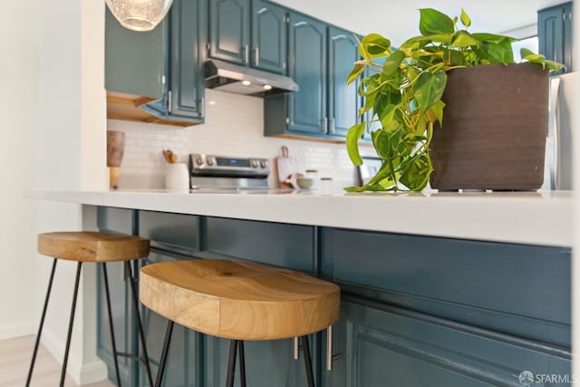1278 La Playa St, San Francisco, CA 94122 - kitchen featuring under cabinet range hood, stainless steel range with electric cooktop, backsplash, and blue cabinetry