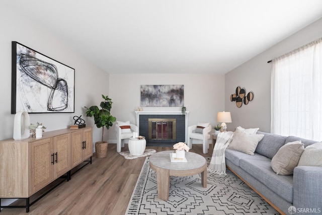living area featuring light wood-style floors and a brick fireplace
