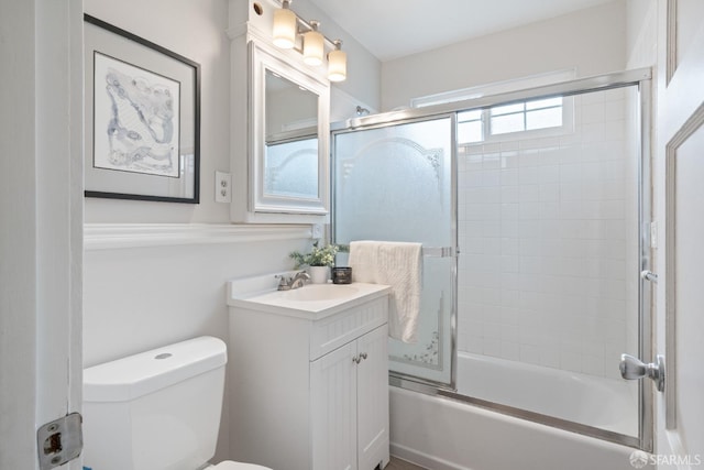 bathroom with toilet, combined bath / shower with glass door, and vanity