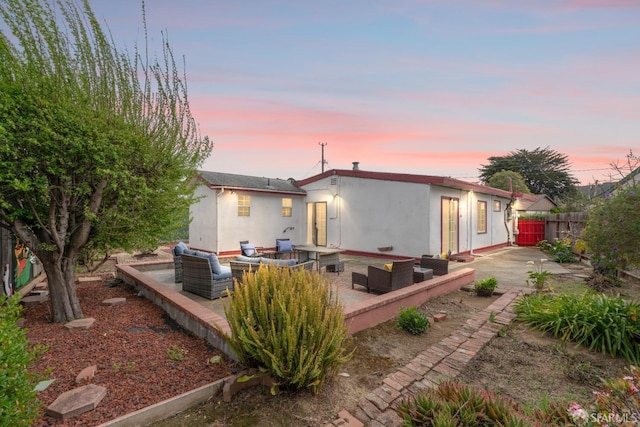 rear view of property featuring a patio area, stucco siding, fence, and an outdoor hangout area